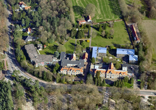 Luchtfoto van een aantal woningen in een groen landschap