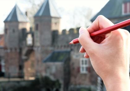 Afbeelding met de Koppelpoort op de achtergrond en een hand met een rood stempotlood op de voorgrond.